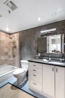 a bathroom with a double vanity sink a toilet a mirror and shower