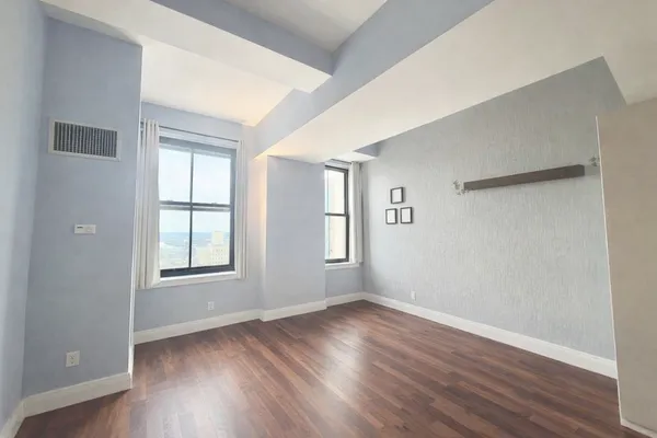 an empty room with wooden floor and windows