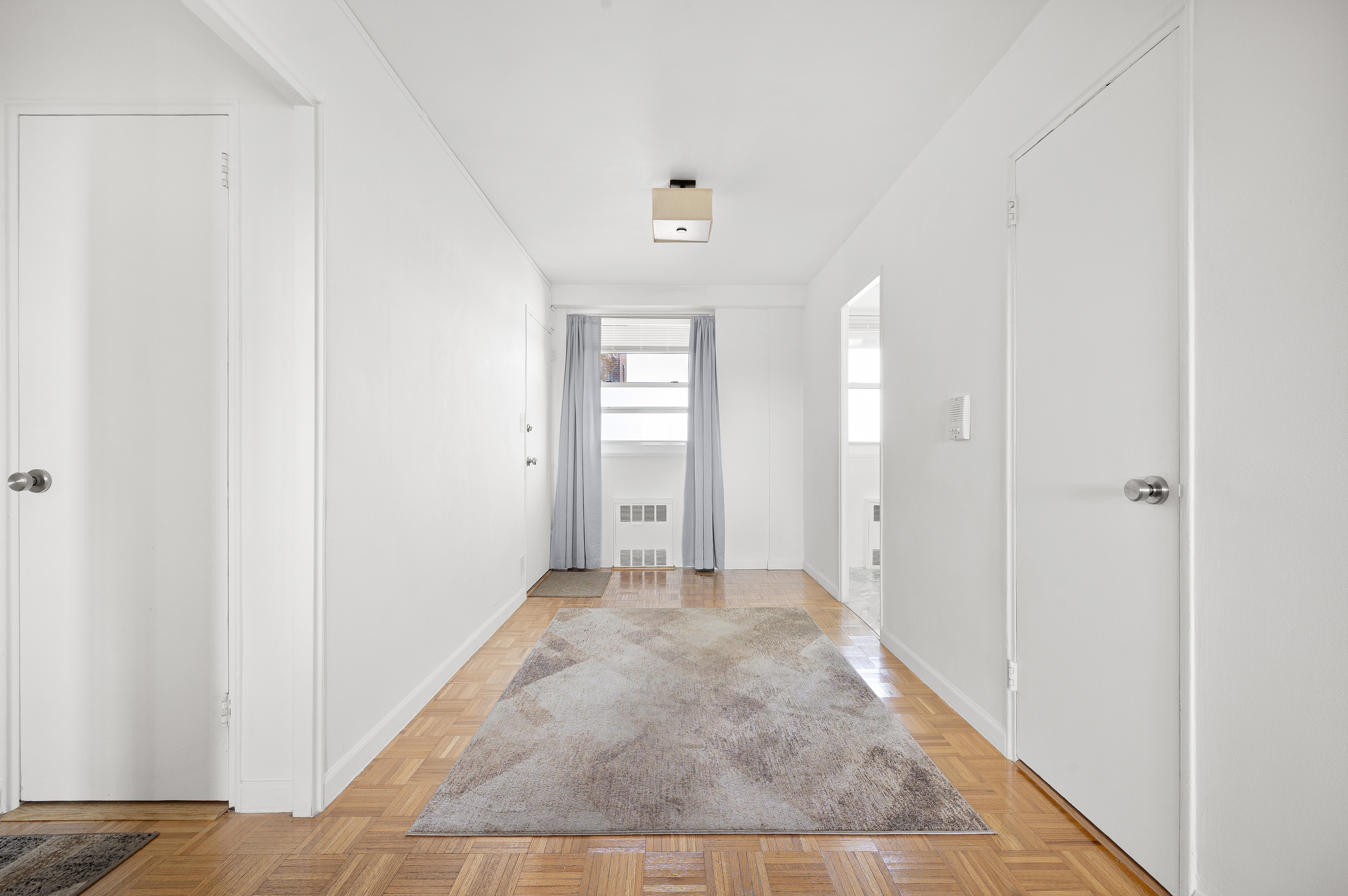 35-11 85th Street, Unit 8M Queens, NY 11372 - Photo 9 of 16 a view of a hallway with wooden floor and a bathroom
