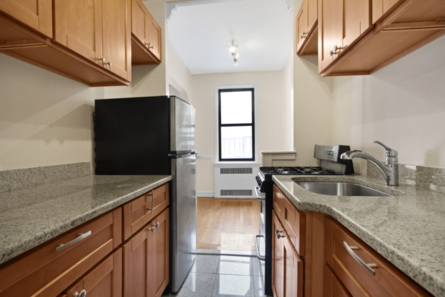 145 East 22nd Street, Unit 5G Manhattan, NY 10010 - Photo 3 of 5 a kitchen with stainless steel appliances granite countertop a sink a stove and a wooden cabinets