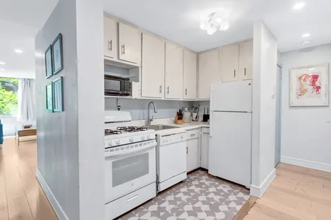 a kitchen with stainless steel appliances granite countertop a refrigerator a stove a sink and white cabinets with wooden floor