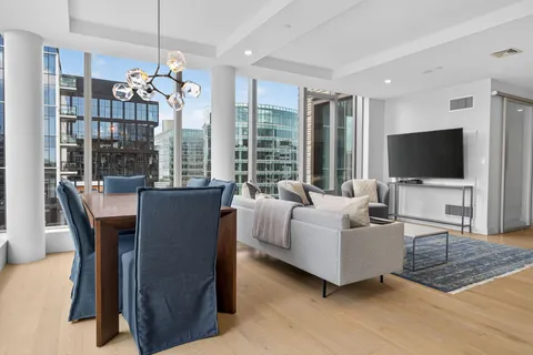 a living room with furniture a flat screen tv and a floor to ceiling window