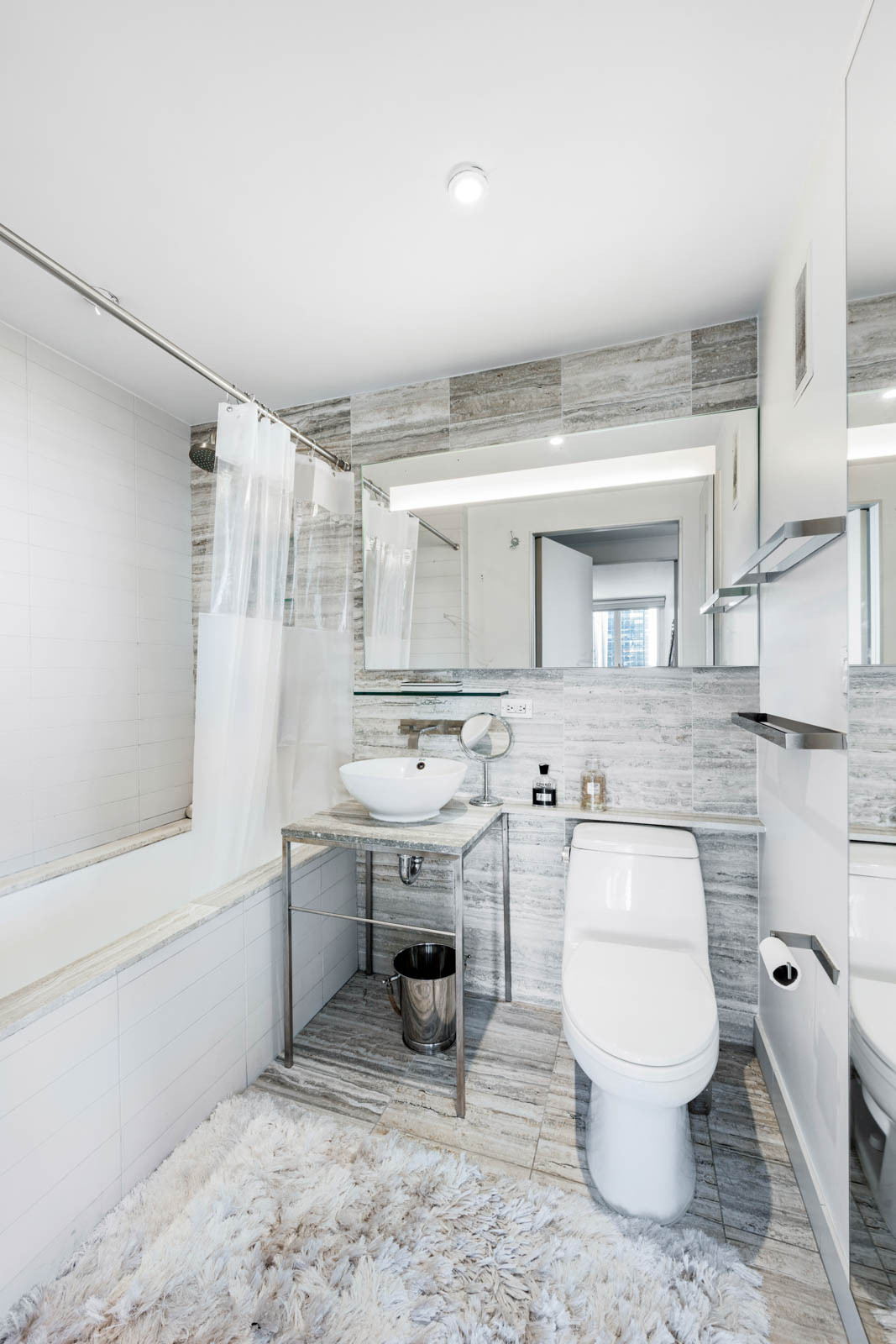 322 West 57th Street, Unit 50H Manhattan, NY 10019 - Photo 6 of 7 a bathroom with a sink toilet a mirror and bathtub