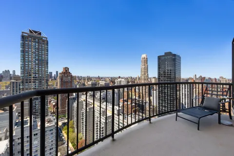 a view of roof deck with wooden fence and city view