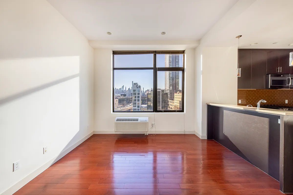 51-42 27th Street, Unit 6C Queens, NY 11101 - Photo 2 of 10 a view of an empty room with window and wooden floor