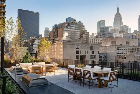 a view of a roof deck with table and chairs and potted plants