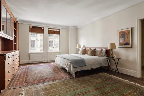 a spacious bedroom with a bed a couch and windows