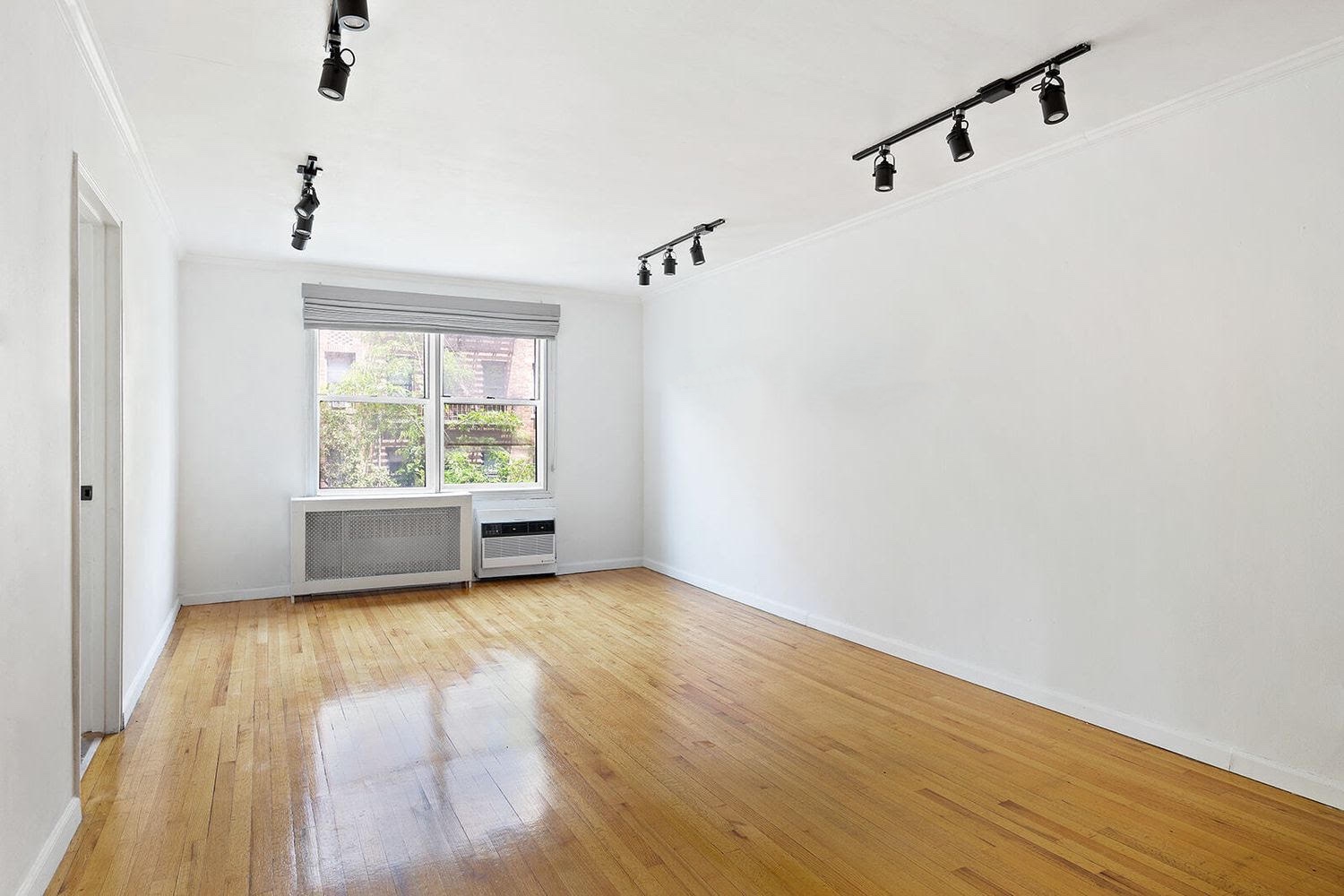 302 East 88th Street, Unit 3F Manhattan, NY 10128 - Photo 2 of 6 a view of an empty room with a window and wooden floor