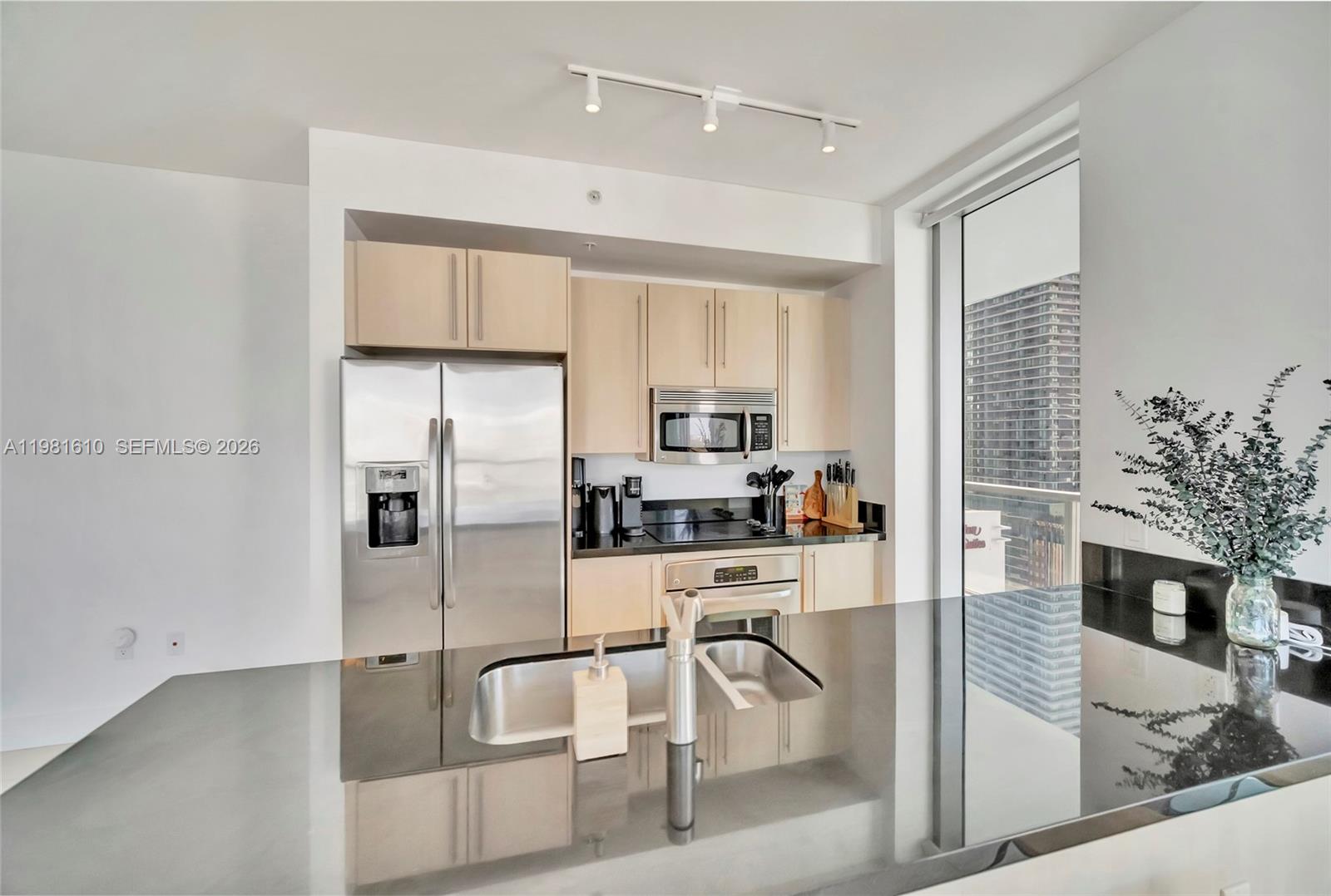79 Southwest 12th Street, Unit 2201S Miami, FL 33130 - Photo 5 of 33 a kitchen with stainless steel appliances granite countertop a refrigerator a stove and white cabinets with wooden floor