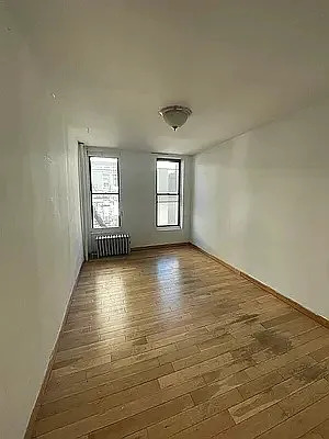 402 East 69th Street, Unit 23 Manhattan, NY 10065 - Photo 2 of 6 an empty room with wooden floor and windows