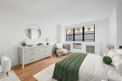 a bedroom with a bed large window and a potted plant