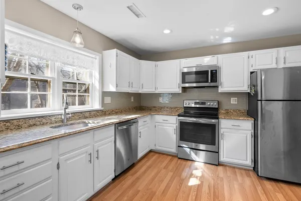 a kitchen with a sink wooden floor and stainless steel appliances