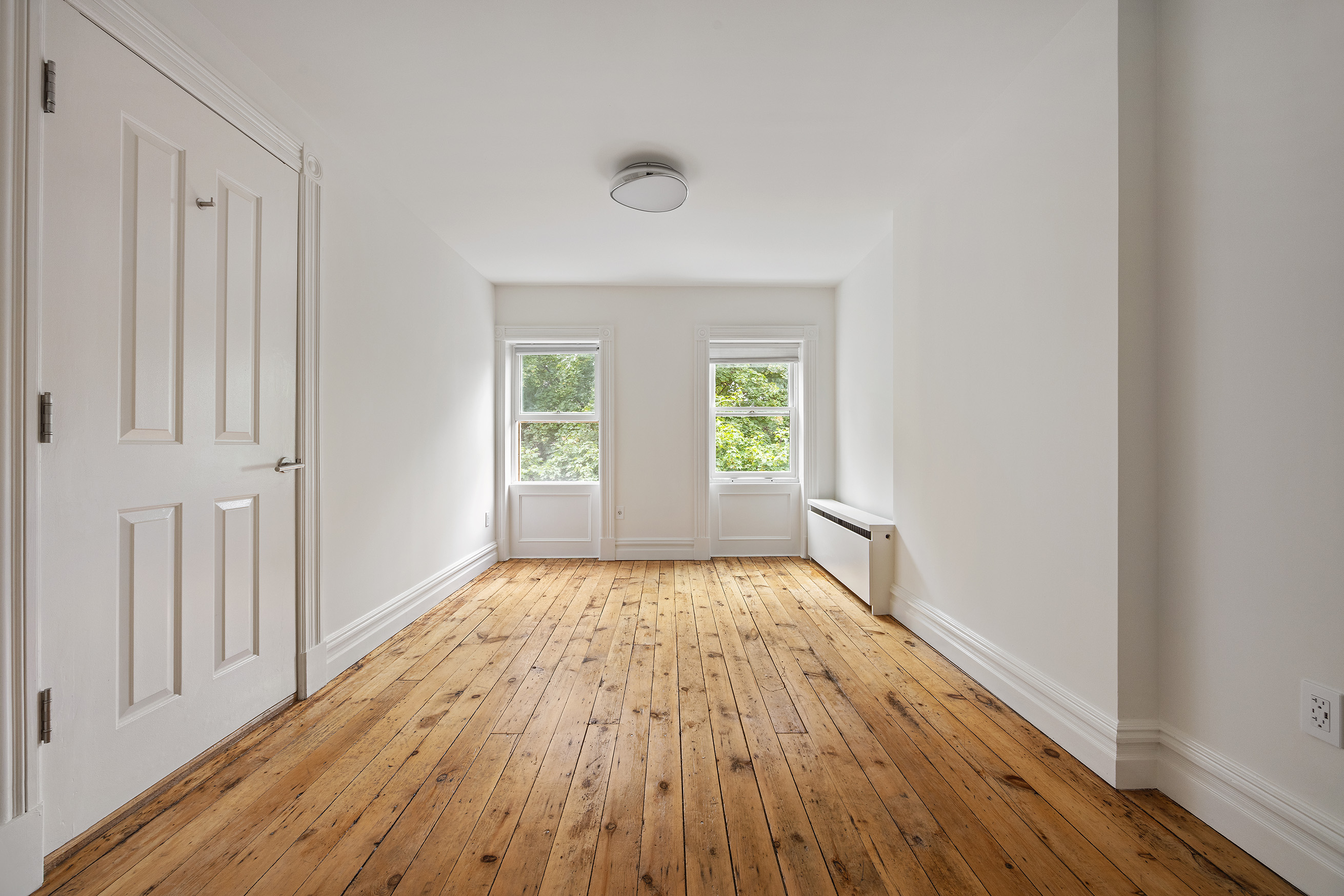 64 Clifton Place, Unit 2 Brooklyn, NY 11238 - Photo 13 of 16 a view of an empty room with wooden floor and a window