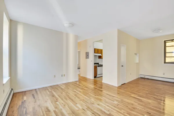 an empty room with wooden floor and windows