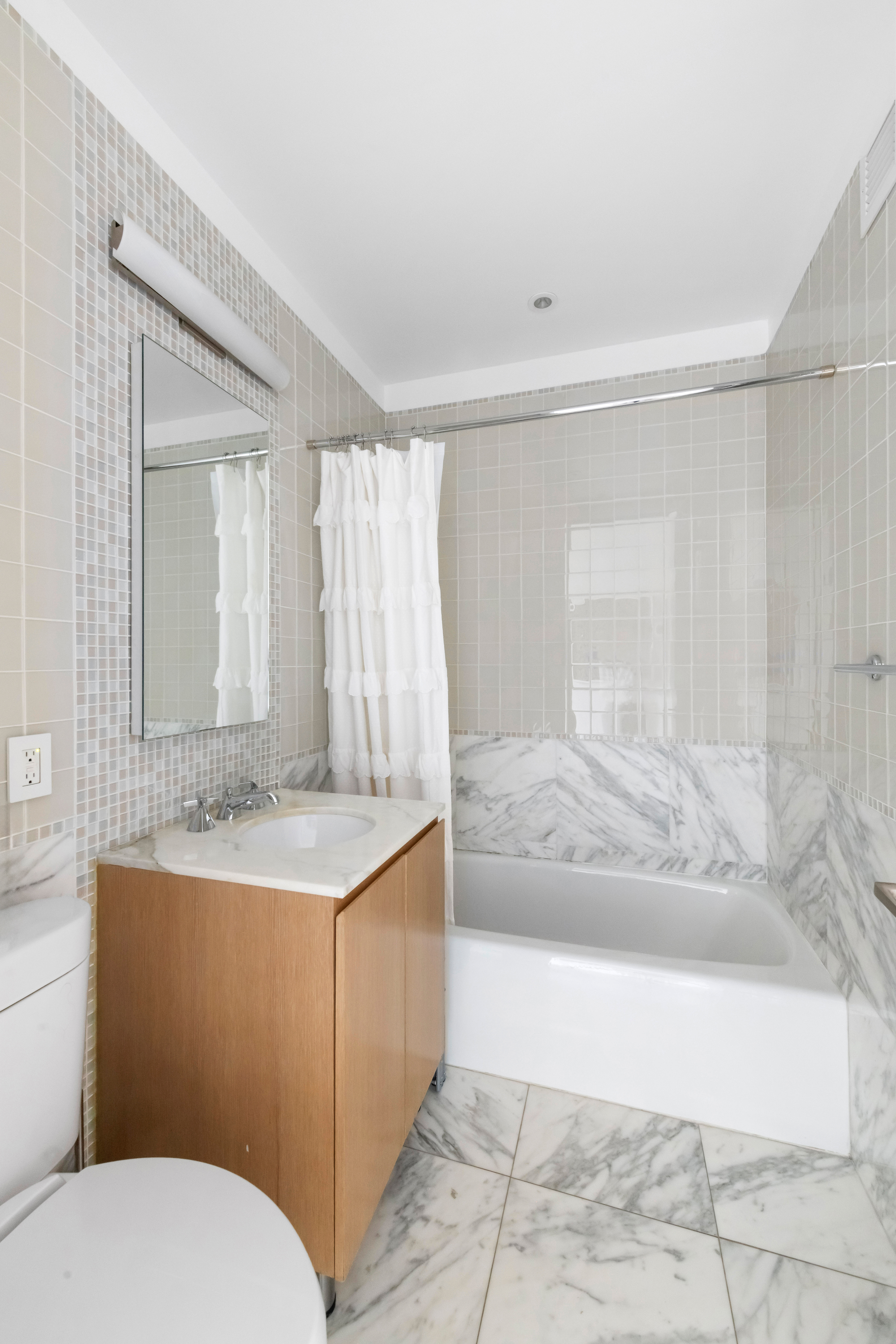 255 East 74th Street, Unit 14C Manhattan, NY 10021 - Photo 12 of 14 a bathroom with a granite countertop sink a toilet a mirror and bathtub