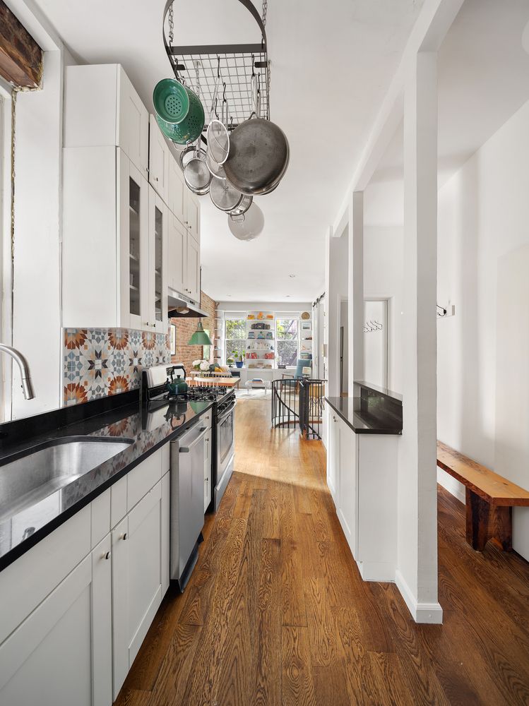 a kitchen with stainless steel appliances granite countertop a sink a stove and a wooden floors