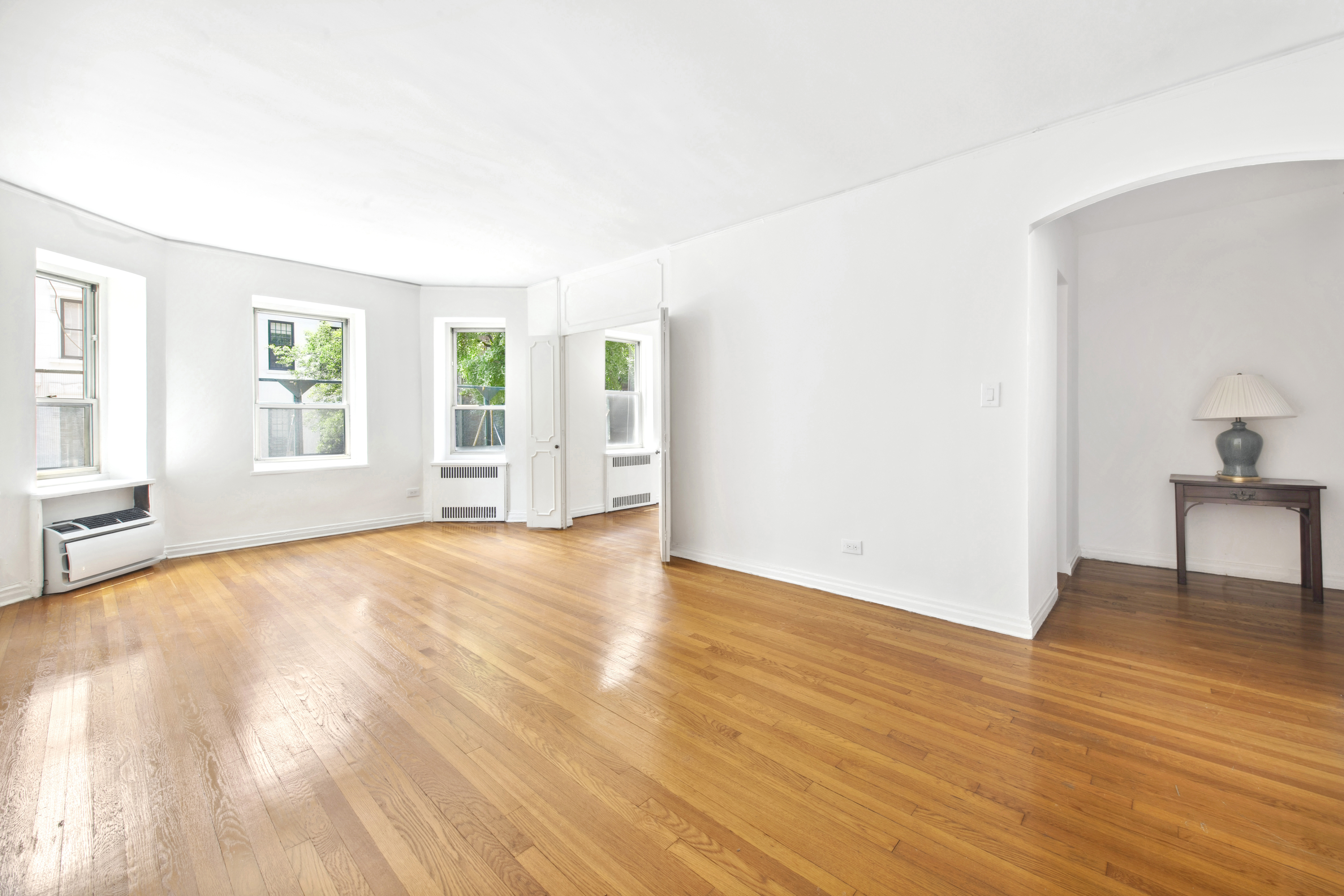 515 East 89th Street, Unit 2E Manhattan, NY 10128 - Photo 2 of 17 an empty room with wooden floor and windows