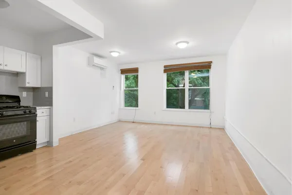 a view of an empty room with a window and wooden floor