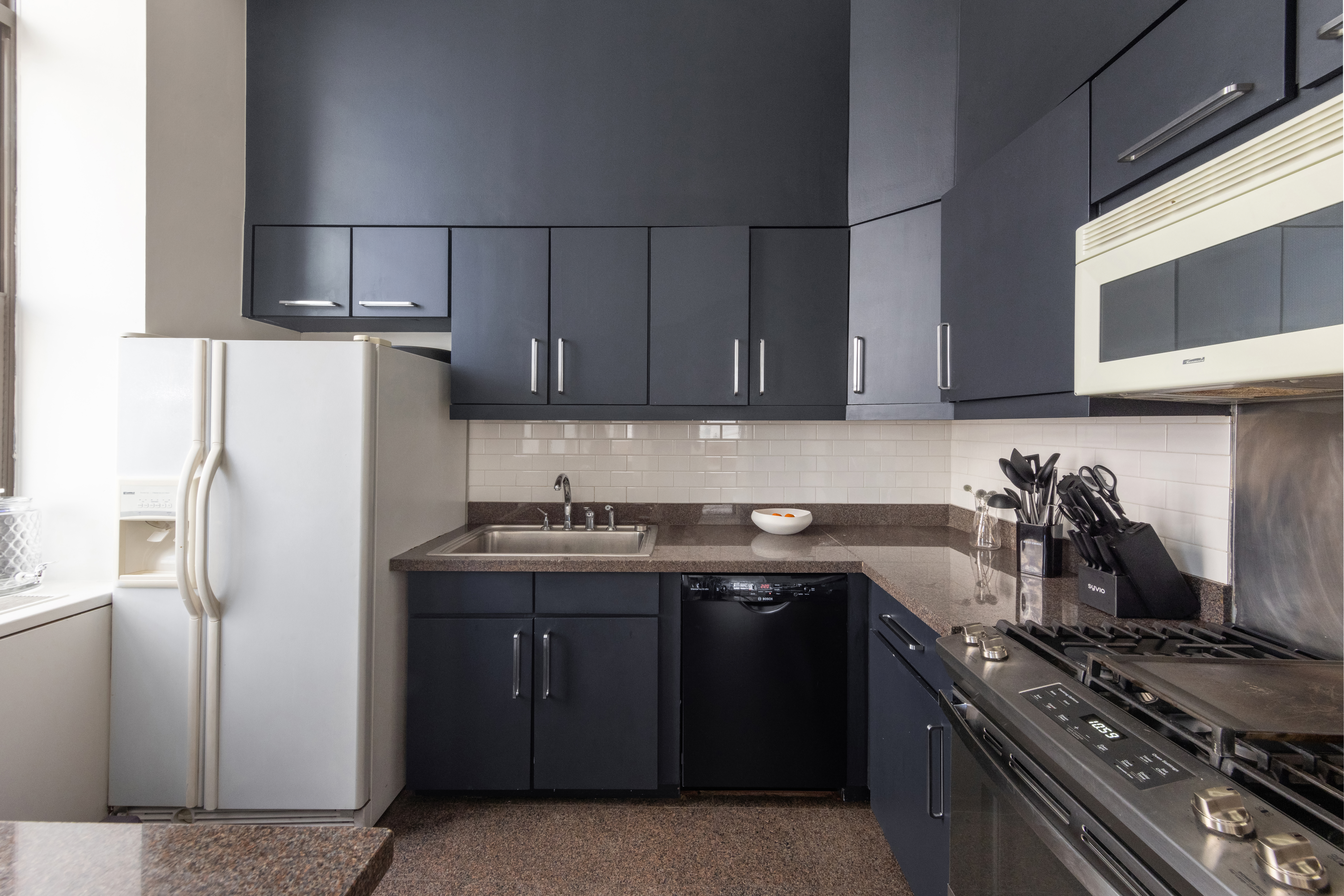 65 Leonard Street, Unit 4 Manhattan, NY 10013 - Photo 5 of 10 a kitchen with stainless steel appliances granite countertop a stove and a refrigerator