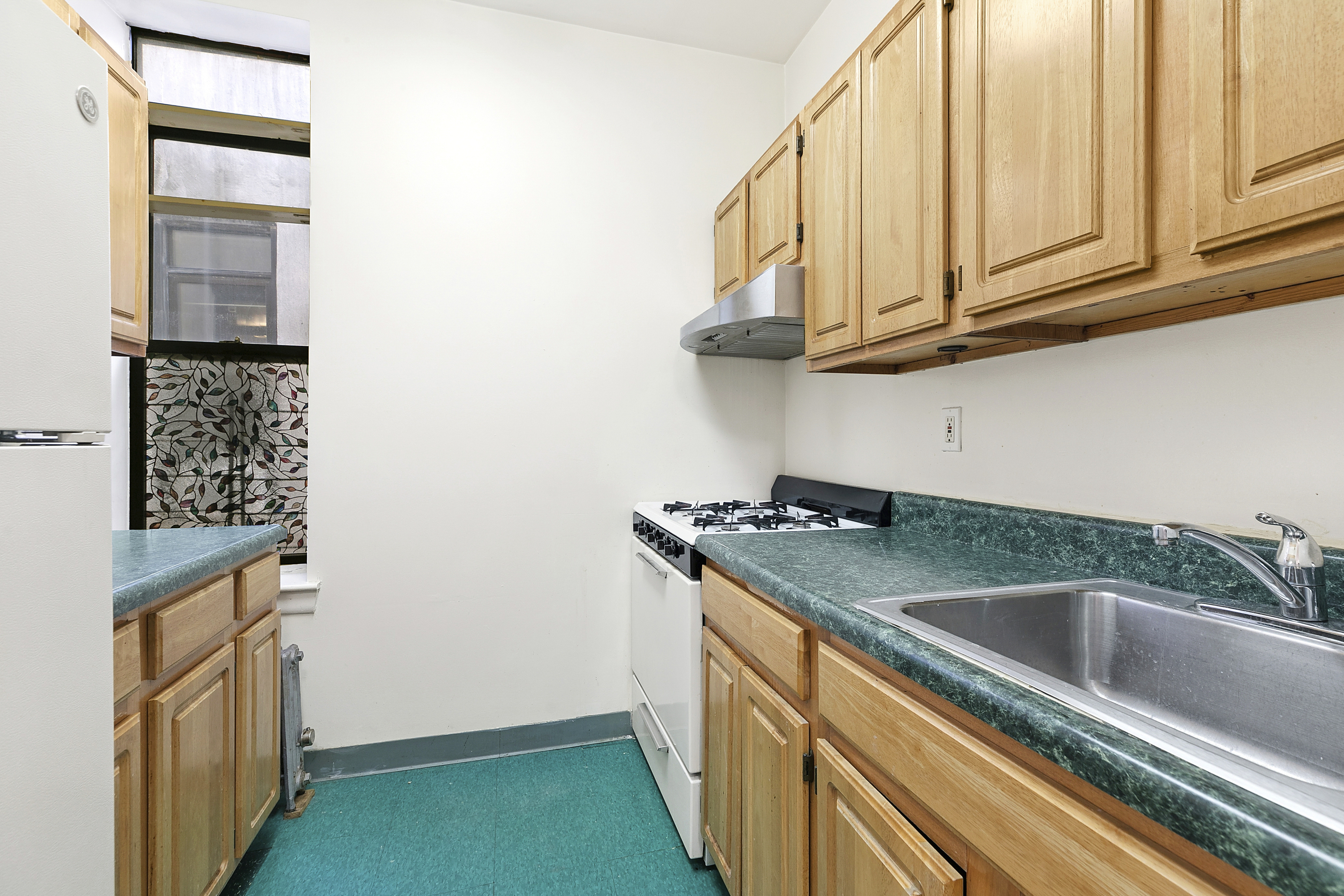 11 St Nicholas Avenue, Unit 5B Manhattan, NY 10026 - Photo 5 of 10 a kitchen with stainless steel appliances granite countertop a sink and a refrigerator