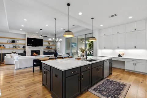 a large kitchen with stainless steel appliances a stove a sink a oven a kitchen island with the wooden floors