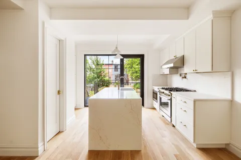 a large white kitchen with granite countertop a large window