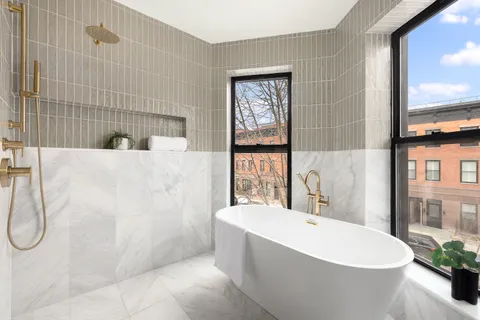 a white bath tub sitting in a bathroom next to a window