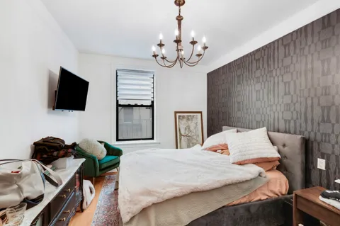 a bedroom with a bed window and a flat screen tv