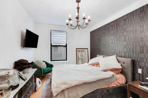 a bedroom with a bed window and a flat screen tv