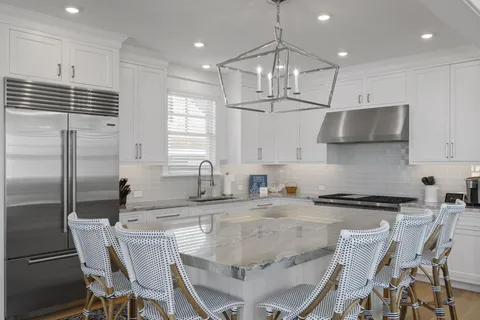 a kitchen with kitchen island granite countertop a sink a counter space appliances and cabinets