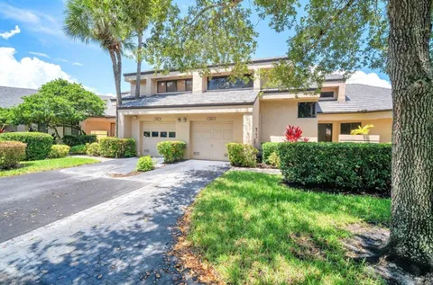 a front view of a house with garden and trees
