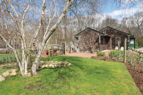 a view of house in front of a big yard with large trees