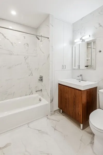 a spacious bathroom with a bathtub shower sink mirror and toilet