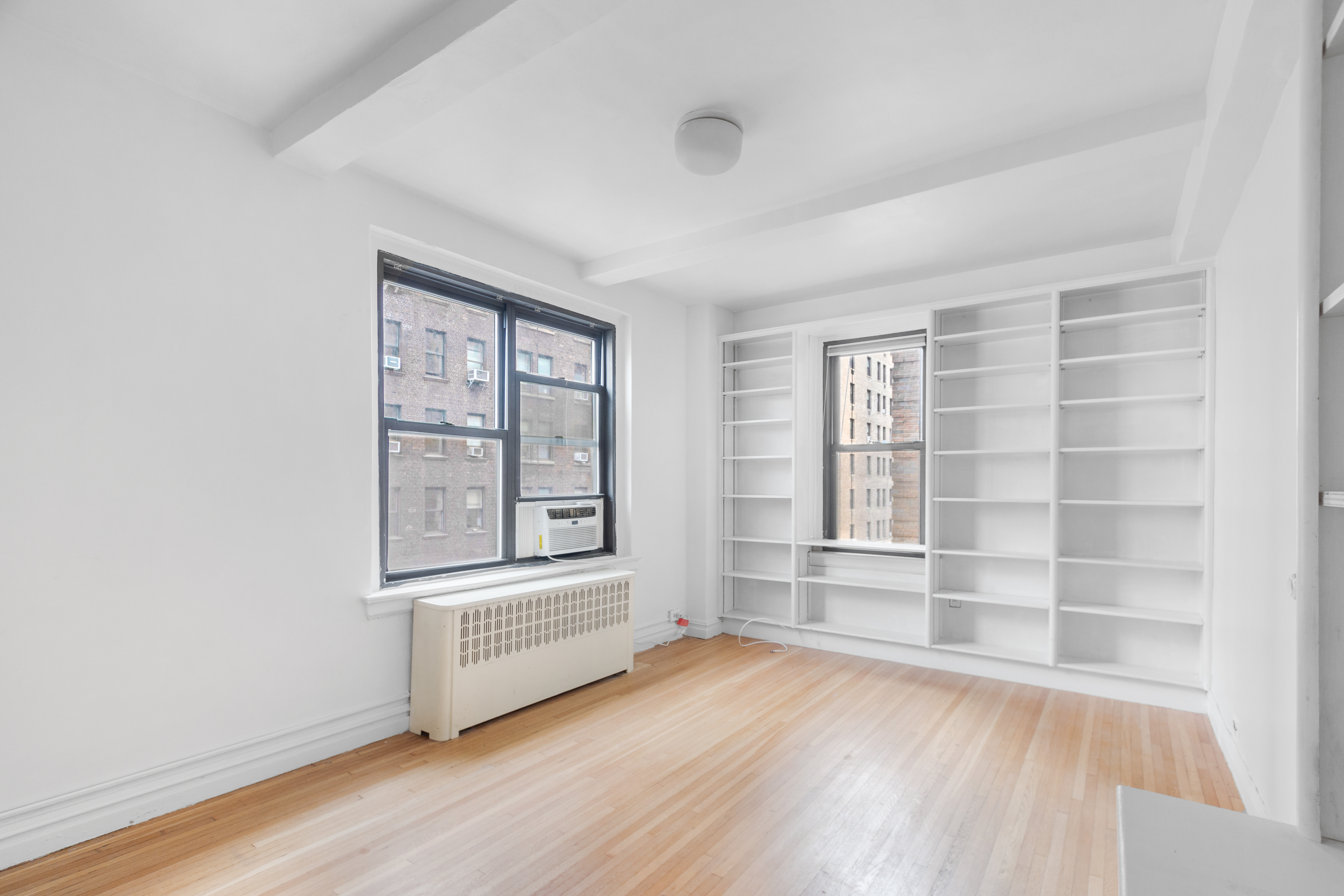 235 West End Avenue, Unit 8G Manhattan, NY 10023 - Photo 12 of 13 an empty room with wooden floor and windows