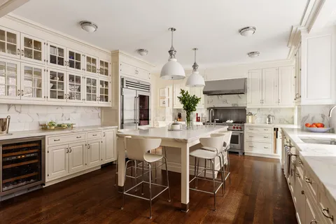 a kitchen with a sink stove and white cabinets with wooden floor