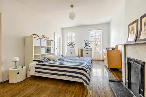a spacious bedroom with a bed and wooden floor