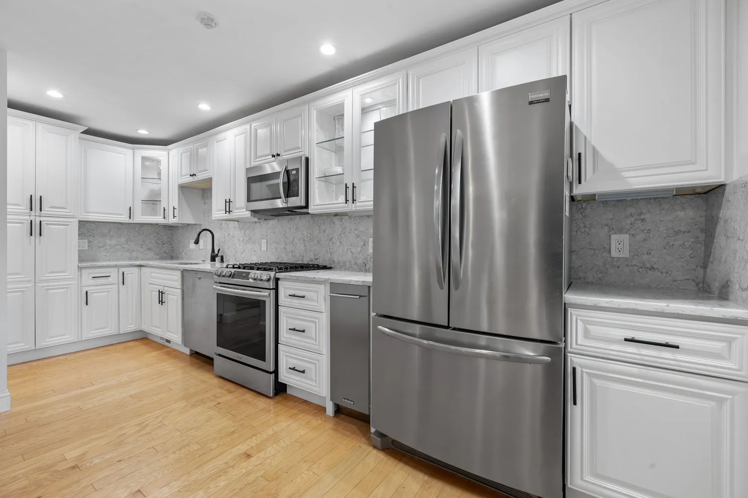 a kitchen with stainless steel appliances white cabinets white refrigerator and a stove top oven