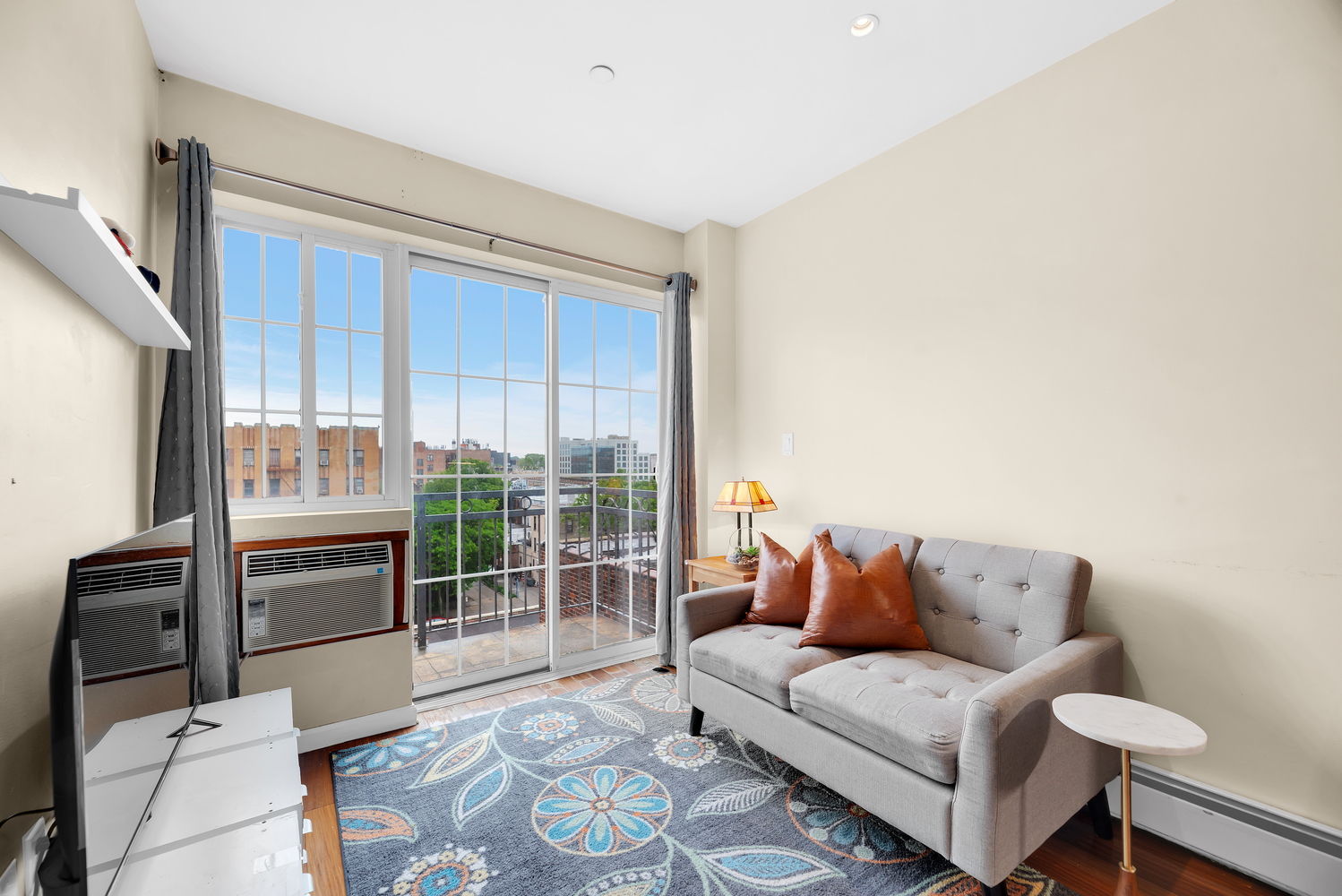 43-33 42nd Street, Unit 6B Queens, NY 11104 - Photo 1 of 8 a living room with furniture and a floor to ceiling window