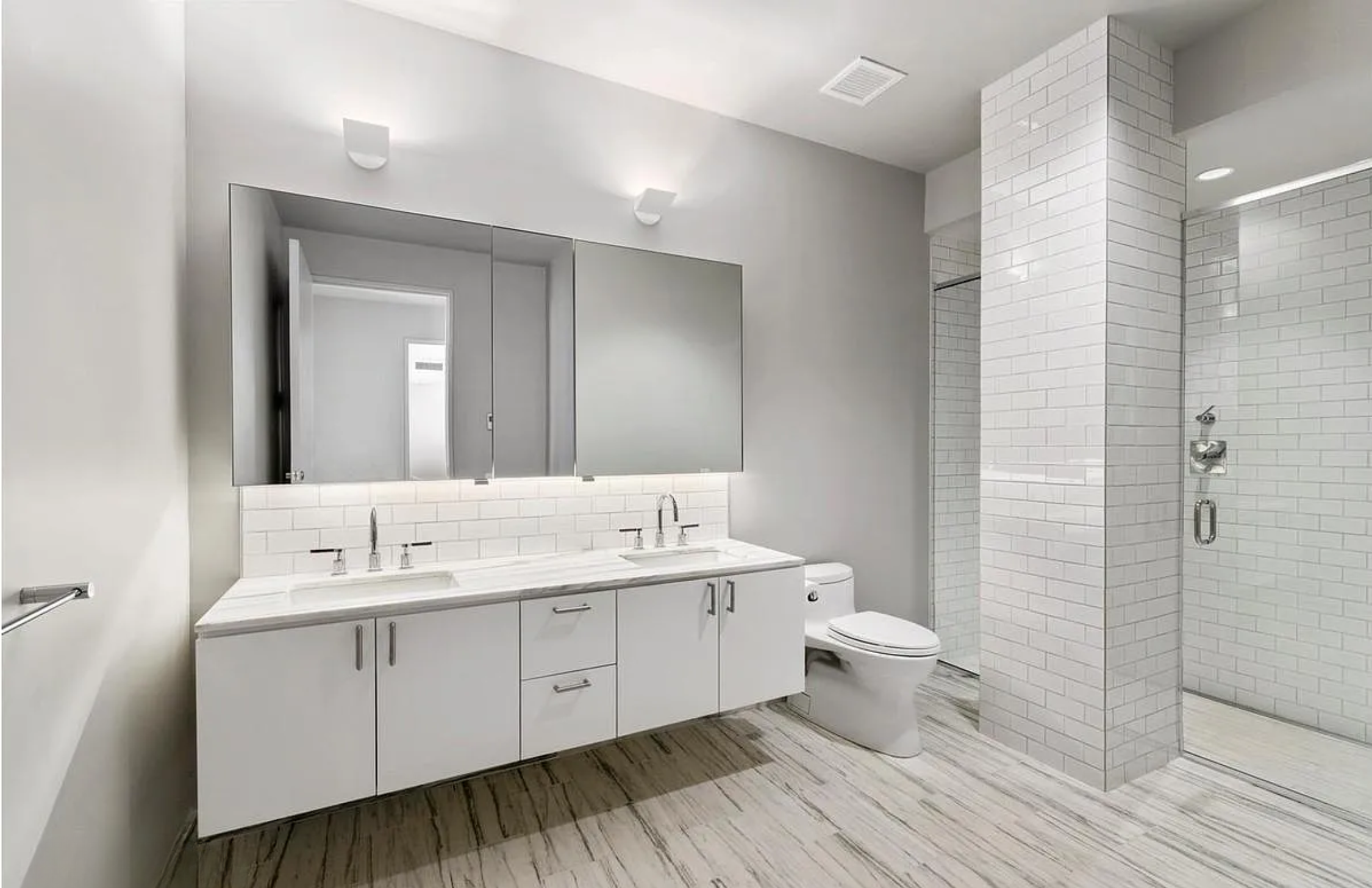 63 Greene Street, Unit 5A Manhattan, NY 10012 - Photo 5 of 9 a spacious bathroom with a double vanity sink and a mirror