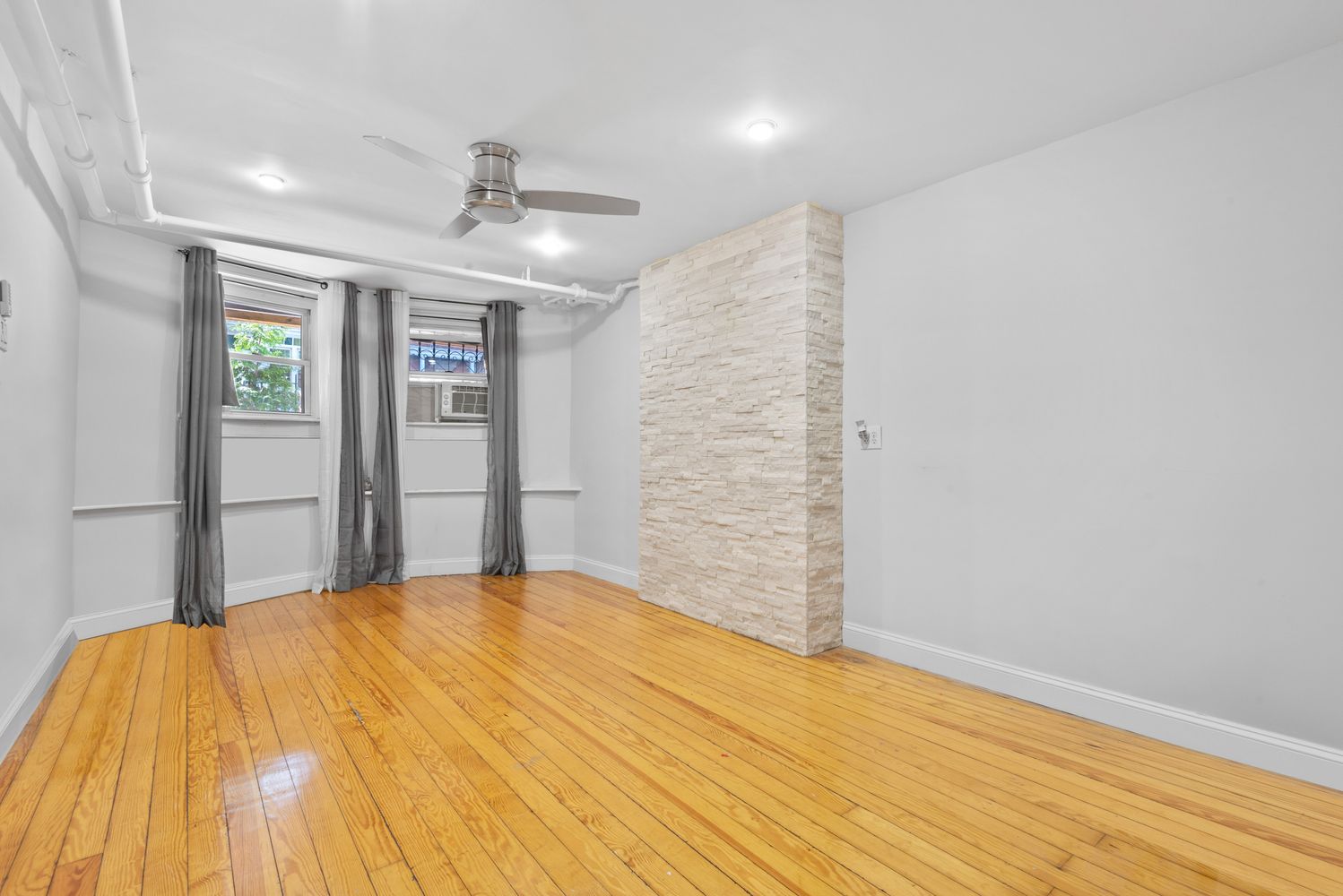 18-91 Stockholm Street, Unit 1 Queens, NY 11385 - Photo 1 of 5 a view of a big room with wooden floor and ceiling fan