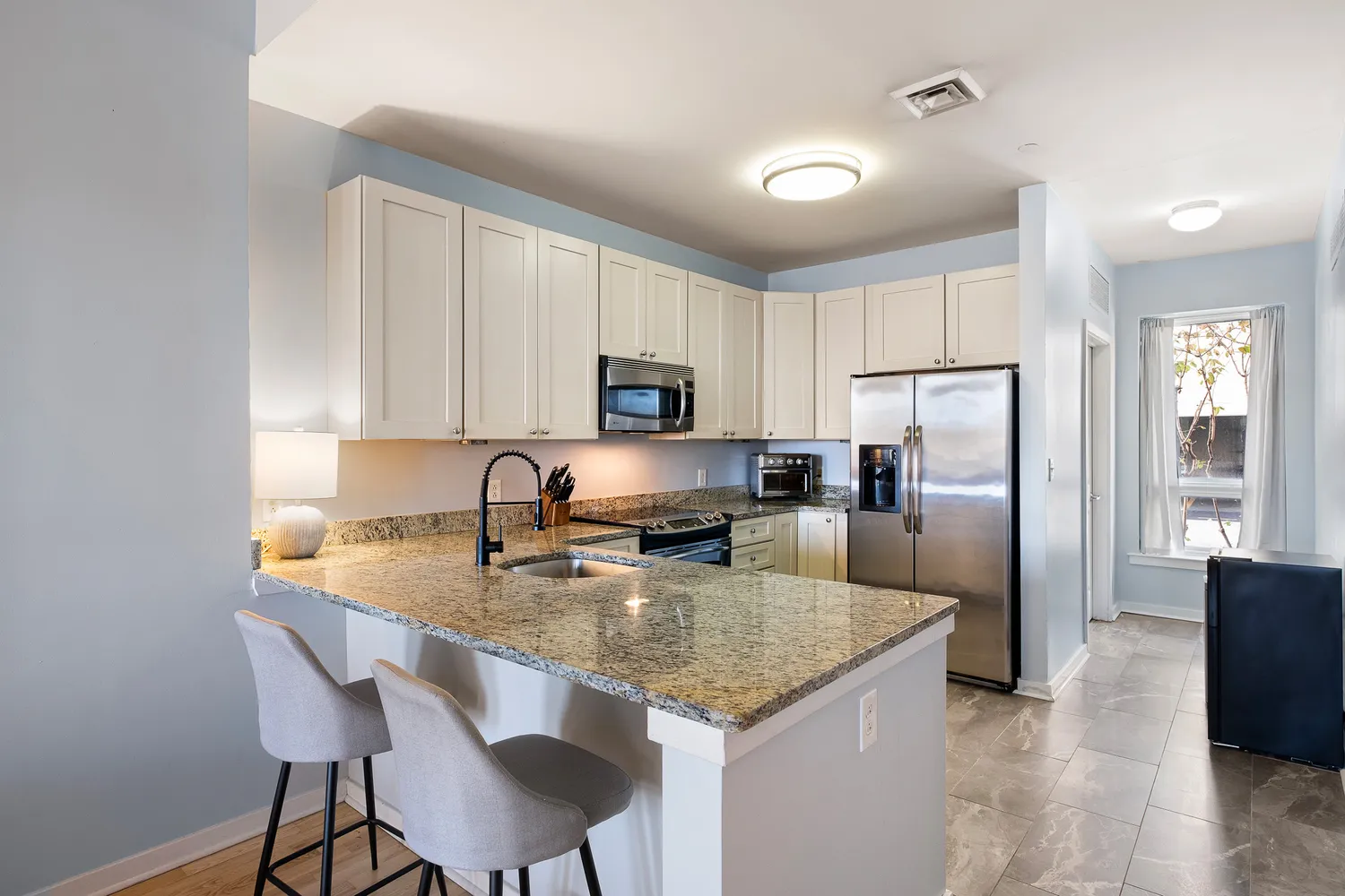 a kitchen with stainless steel appliances granite countertop a refrigerator a stove a sink a stove a dining table and chairs