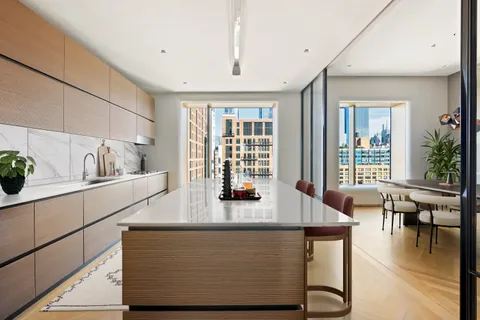 a dining hall with stainless steel appliances granite countertop a stove a sink a dining table and chairs with wooden floor