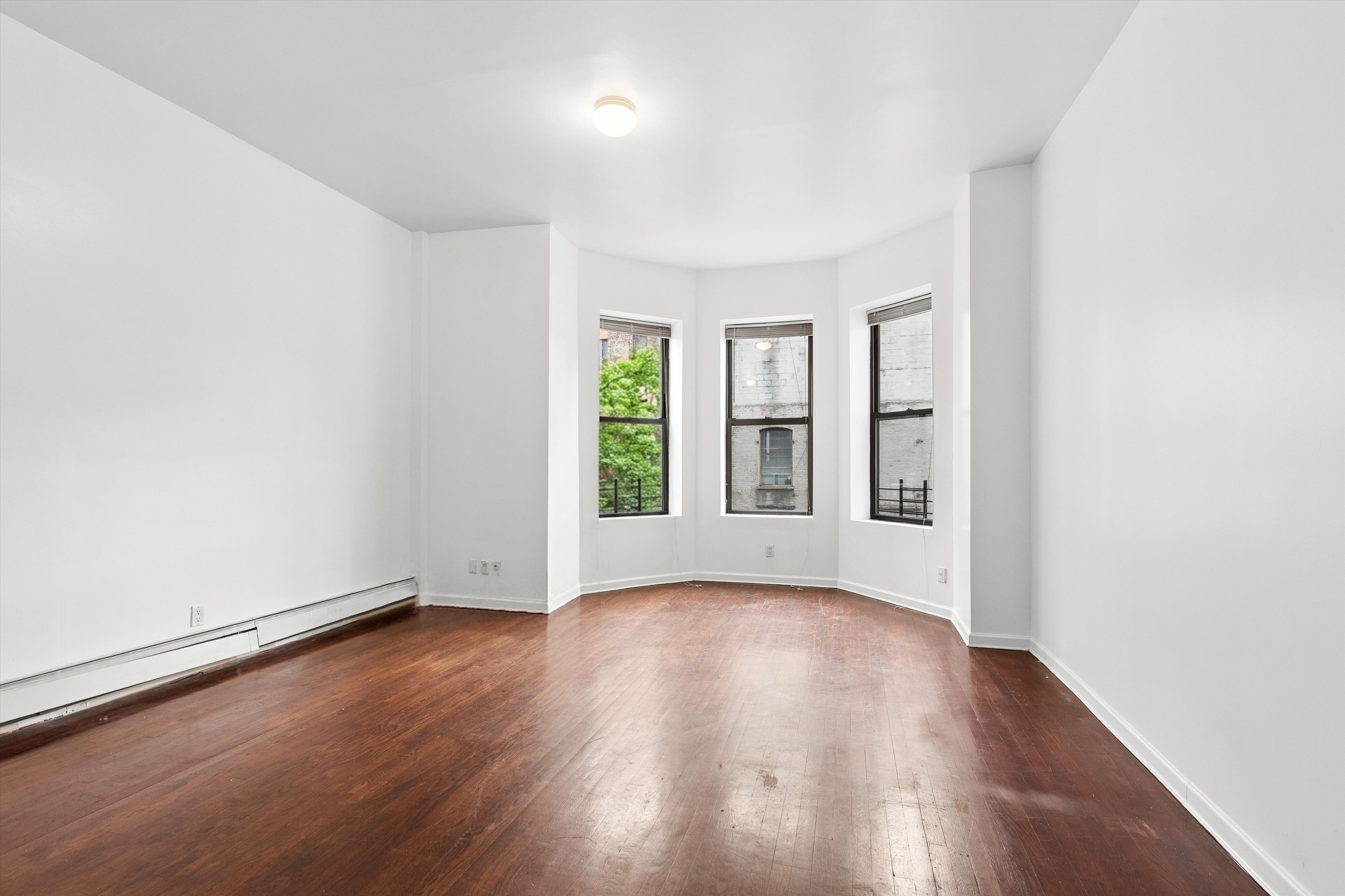 165 West 126th Street Manhattan, NY 10027 - Photo 22 of 40 an empty room with wooden floor and windows