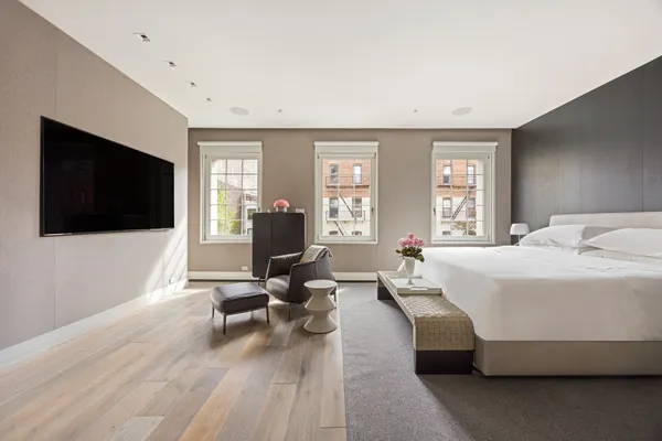 a spacious bedroom with a bed a couch and a large window