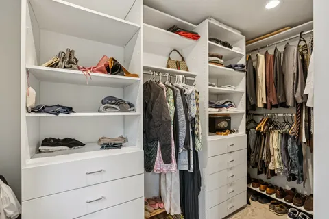 a view of walk in closet with clothes and shoes