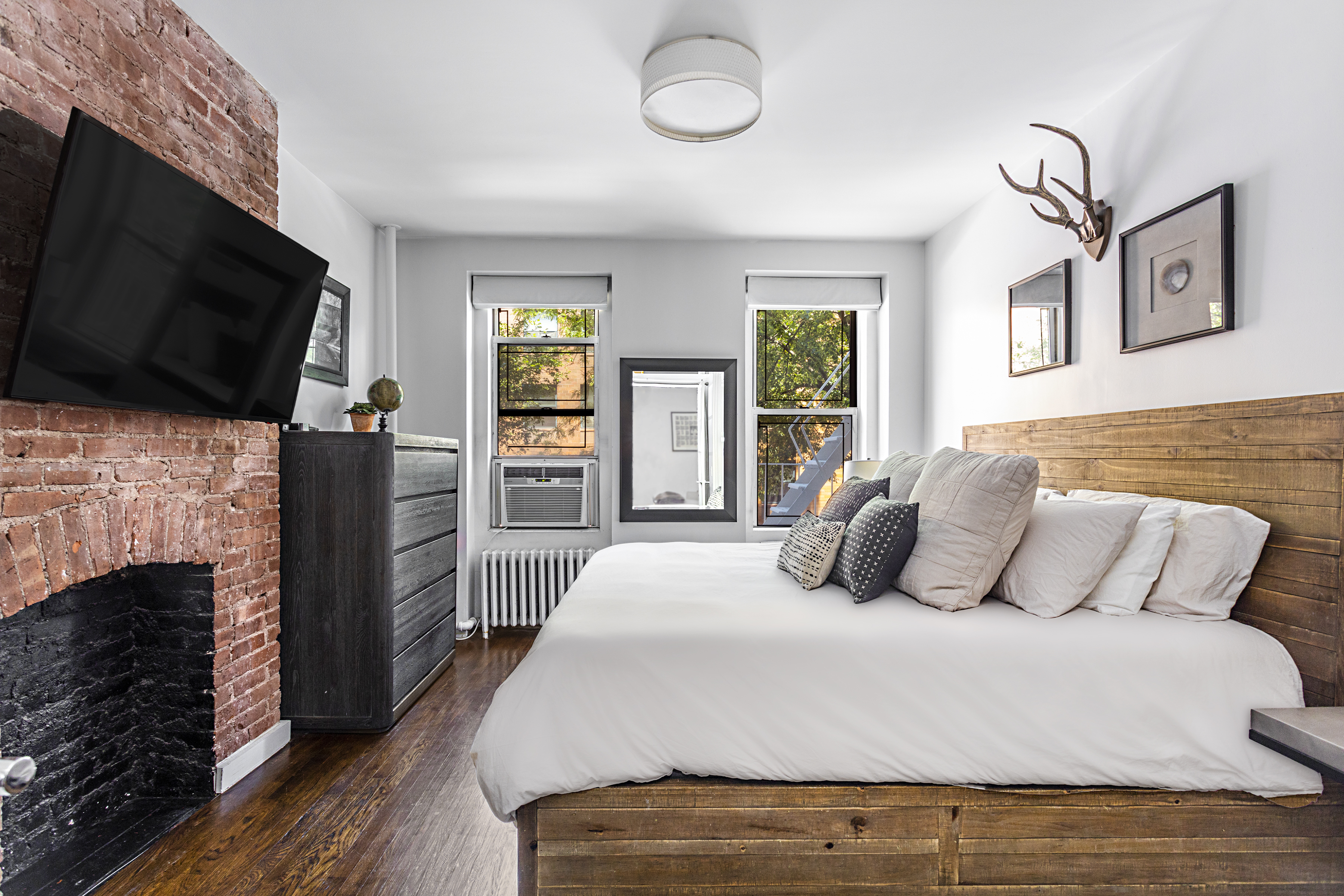 236 East 6th Street, Unit 2W Manhattan, NY 10003 - Photo 5 of 7 a bedroom with furniture a flat screen tv and a fireplace