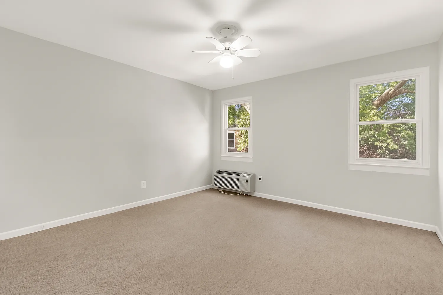 an empty room with windows and ceiling fan