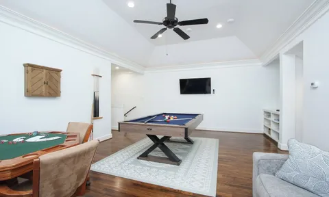 a living room with furniture pool table and white walls