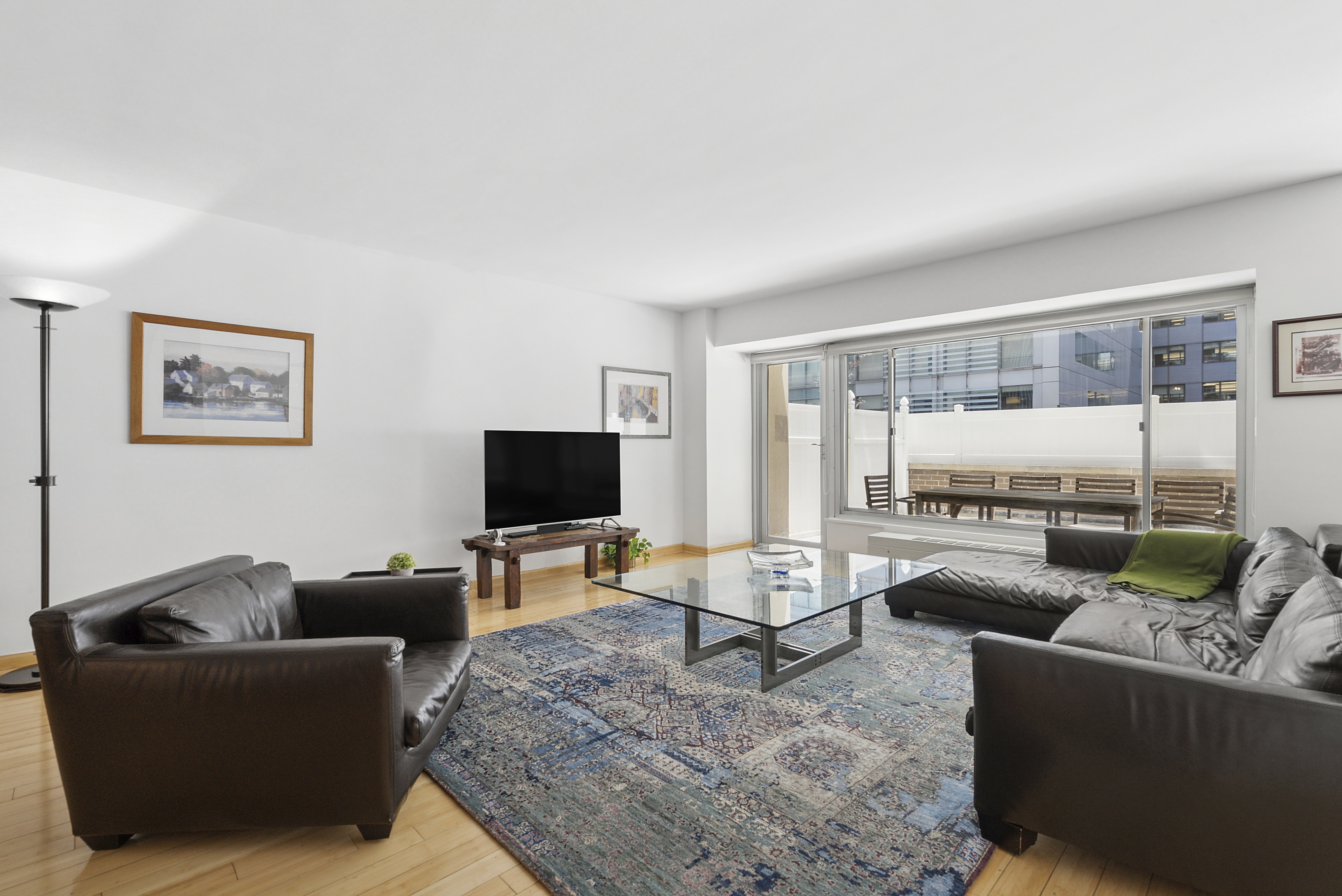 118 East 60th Street, Unit 4H Manhattan, NY 10022 - Photo 2 of 10 a living room with furniture and a flat screen tv