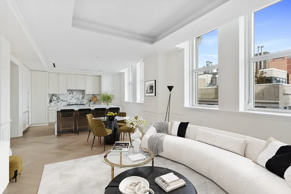 a living room with furniture kitchen view and large windows